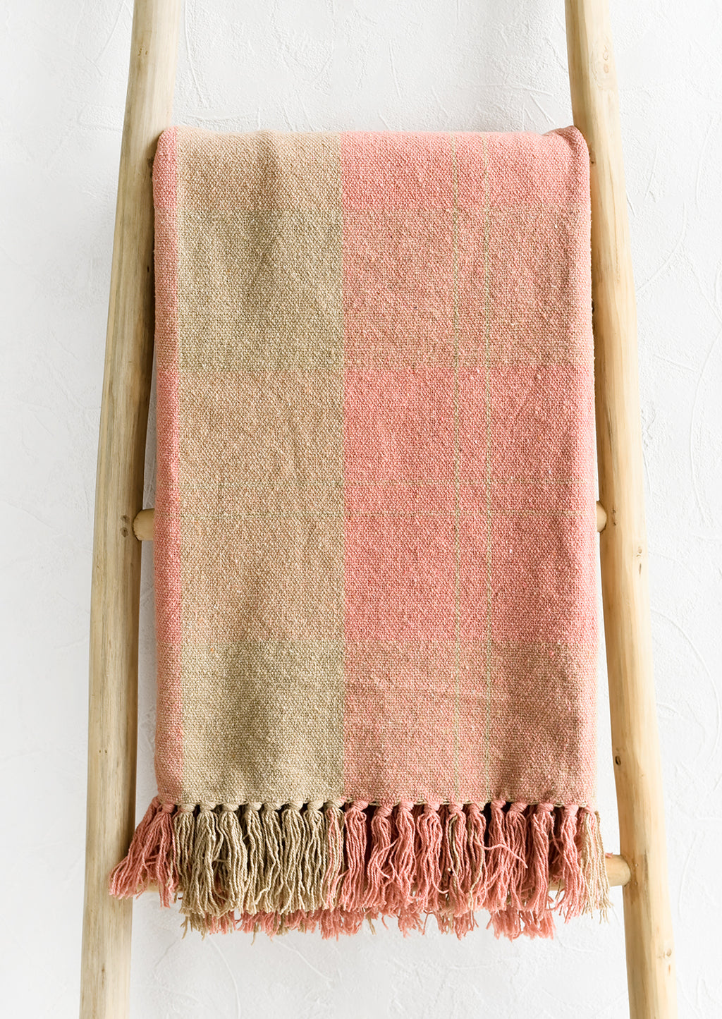 1: A cotton blank in peach and tan check pattern with fringe trim.