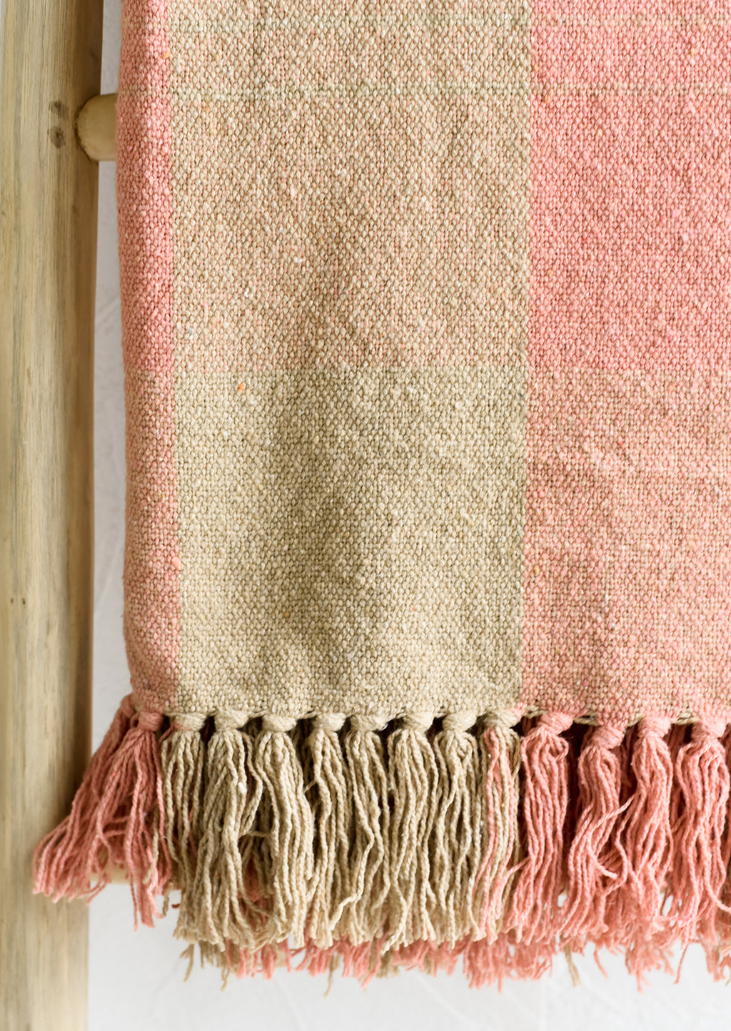 2: A cotton blank in peach and tan check pattern with fringe trim.