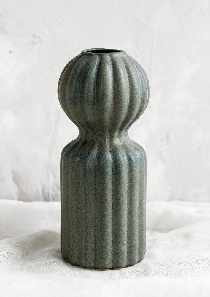A curvy ceramic vase in teal glaze with ball-shaped top.