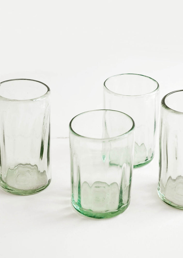 Four horizontally ribbed tumblers in thick green hued glass.