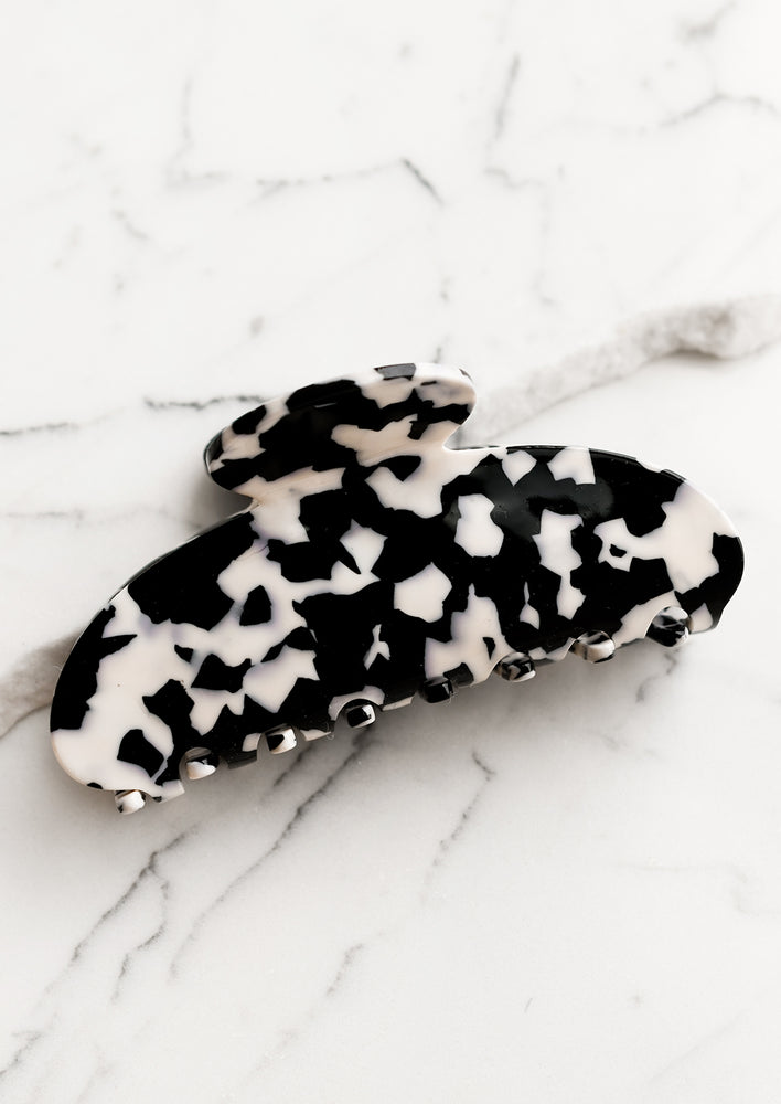 A terrazzo hair claw in black with white spots.