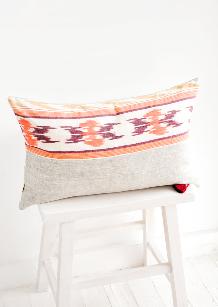 2: Rectangular throw pillow in mixed fabrics. Top half is ikat print in orange and red, bottom half is plain linen.