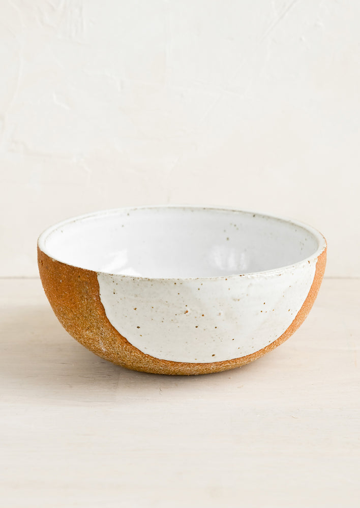 A ceramic bowl in sandy clay with speckled white half moon design.