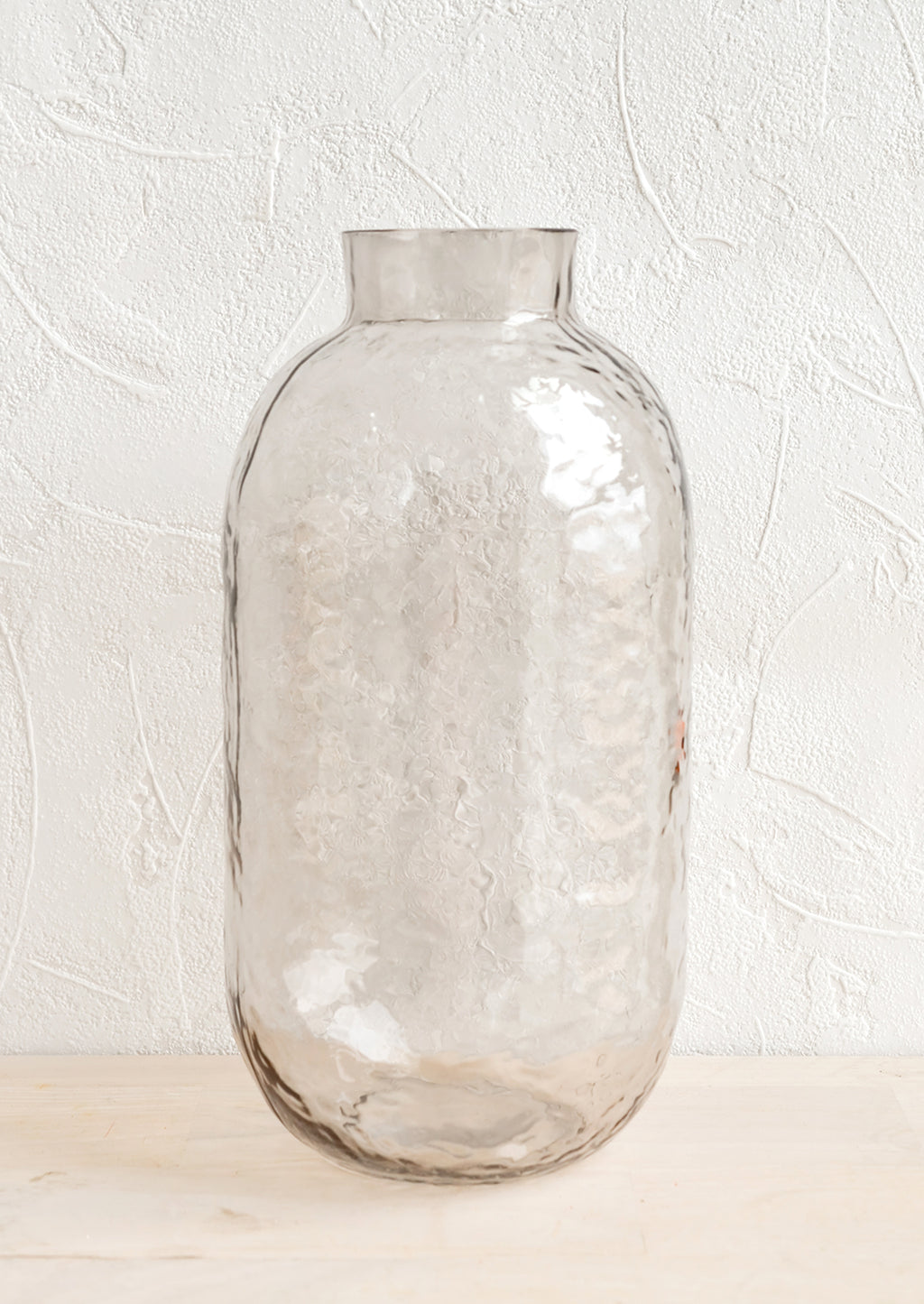Smoke: A tall glass vase with hammered texture in pale grey.