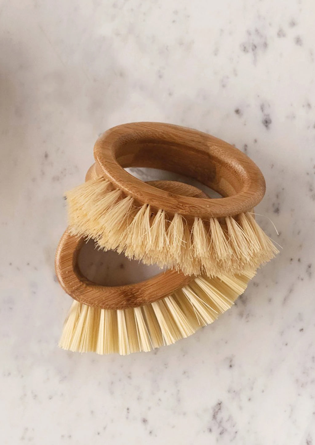 2: Oval-shaped handheld kitchen brushes on a marble countertop