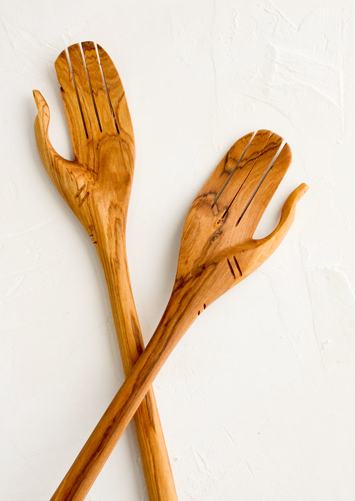 A pair of wooden salad servers carved in the shape of a pair of hands.