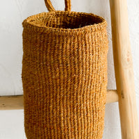 Ochre: An oblong cylindrical basket woven from sisal in ochre color.