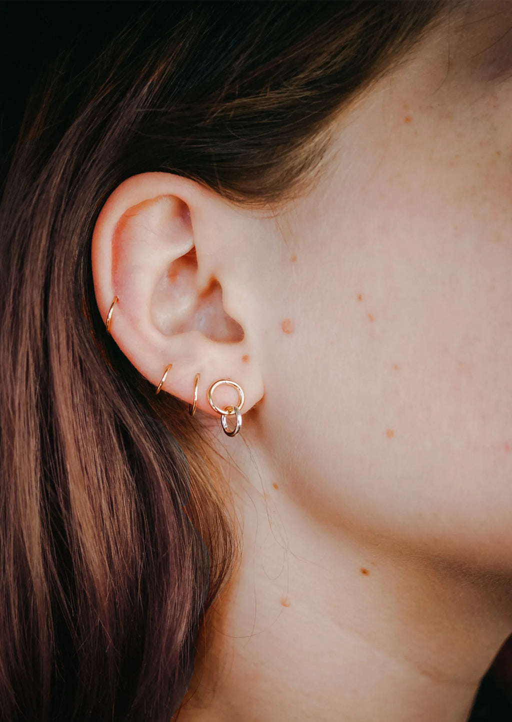 2: A pair of double circle gold earrings on a model.