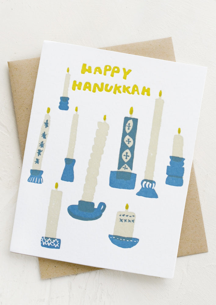 Card with various white and blue candles, text reads "Happy Hanukkah".