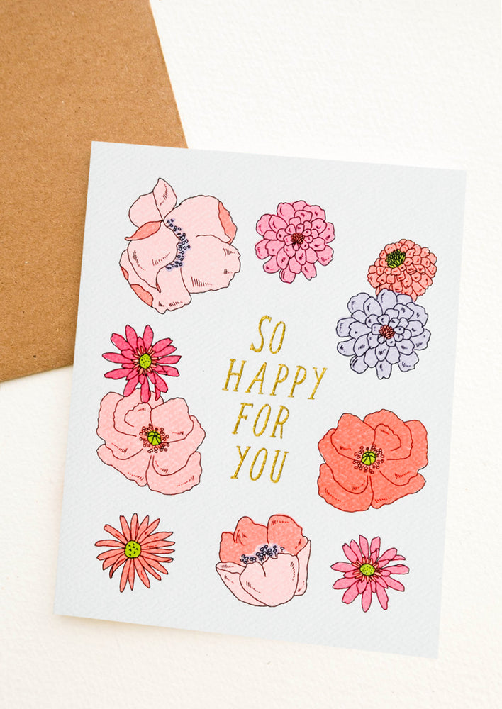 1: A floral print greeting card with gold text reading "So Happy For You".