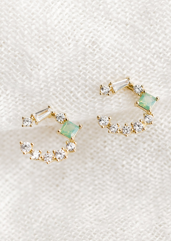 A pair of stud earrings with 3/4 hoop shape in clear crystals with green crystal square.