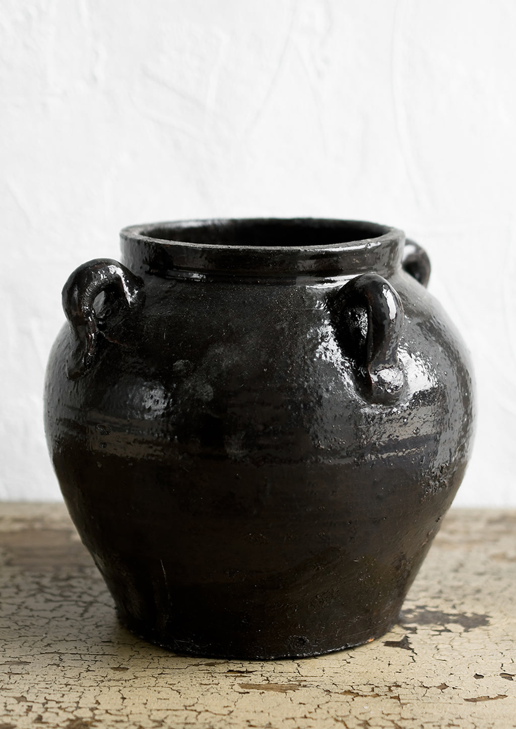 2: A dark brown (almost black) ceramic jar with decorative loop handles.