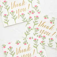 1: A set of identically printed thank you cards. Pink thistle print with gold "thank you!" in cursive.