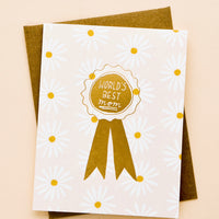 2: Greeting card with allover daisy pattern and gold ribbon reading "World's Best Mom" 