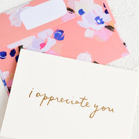 1: A white greeting card with golden cursive reading "I Appreciate You", paired with floral print envelope.