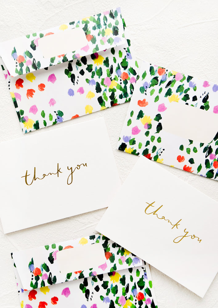 White greeting cards with gold "Thank You" text and floral patterned envelopes