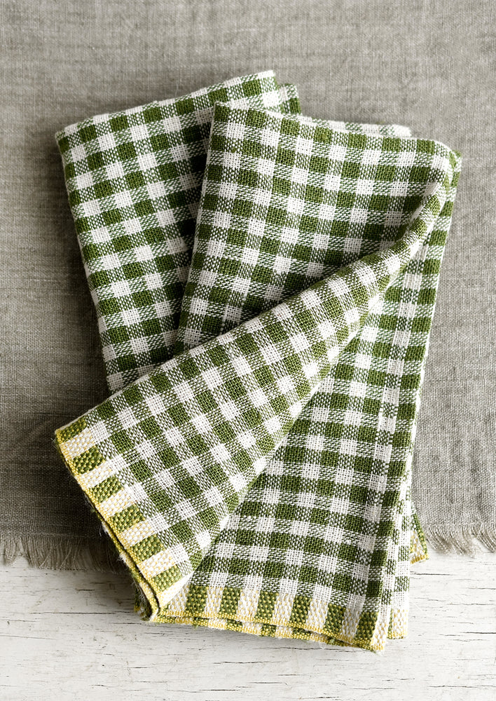 A pair of thick linen dinner napkins in olive gingham.