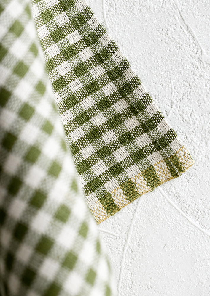 2: A woven gingham textile with contrast thread detailing along edge.