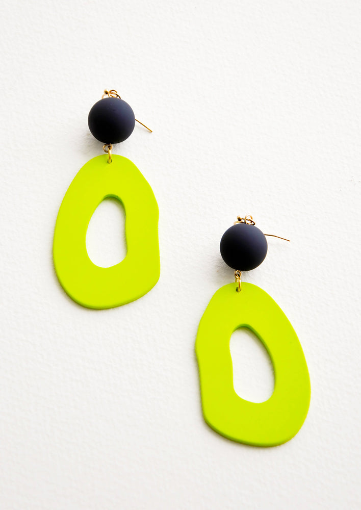 Dangling earrings featuring asymmetric lime green cut out oval hanging from black bead.