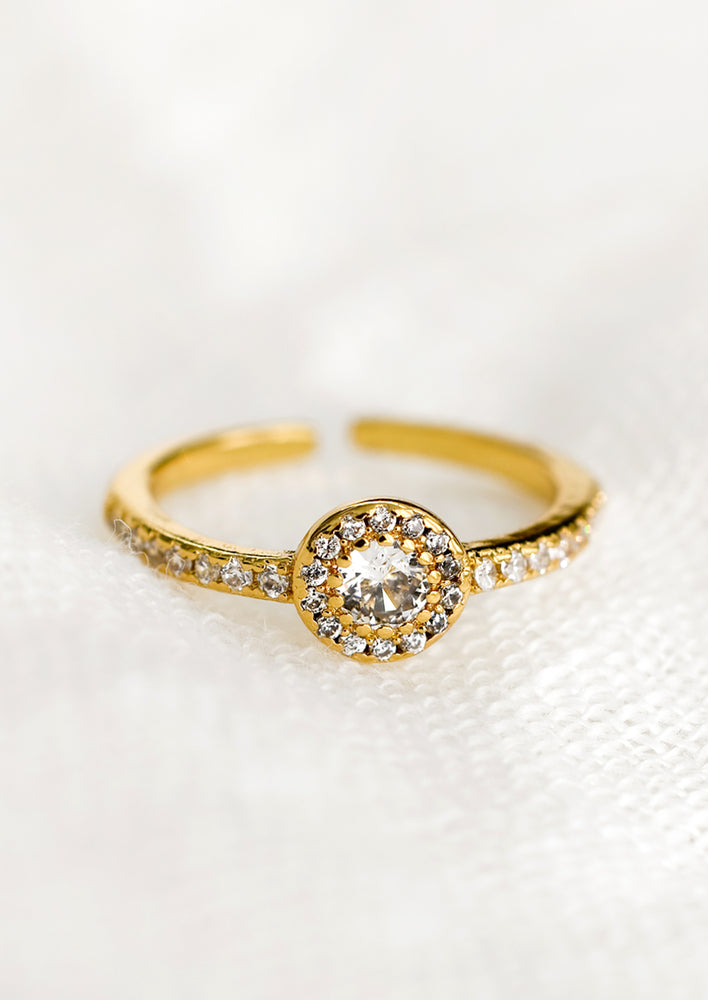 A gold ring with crystal band and round crystal setting.