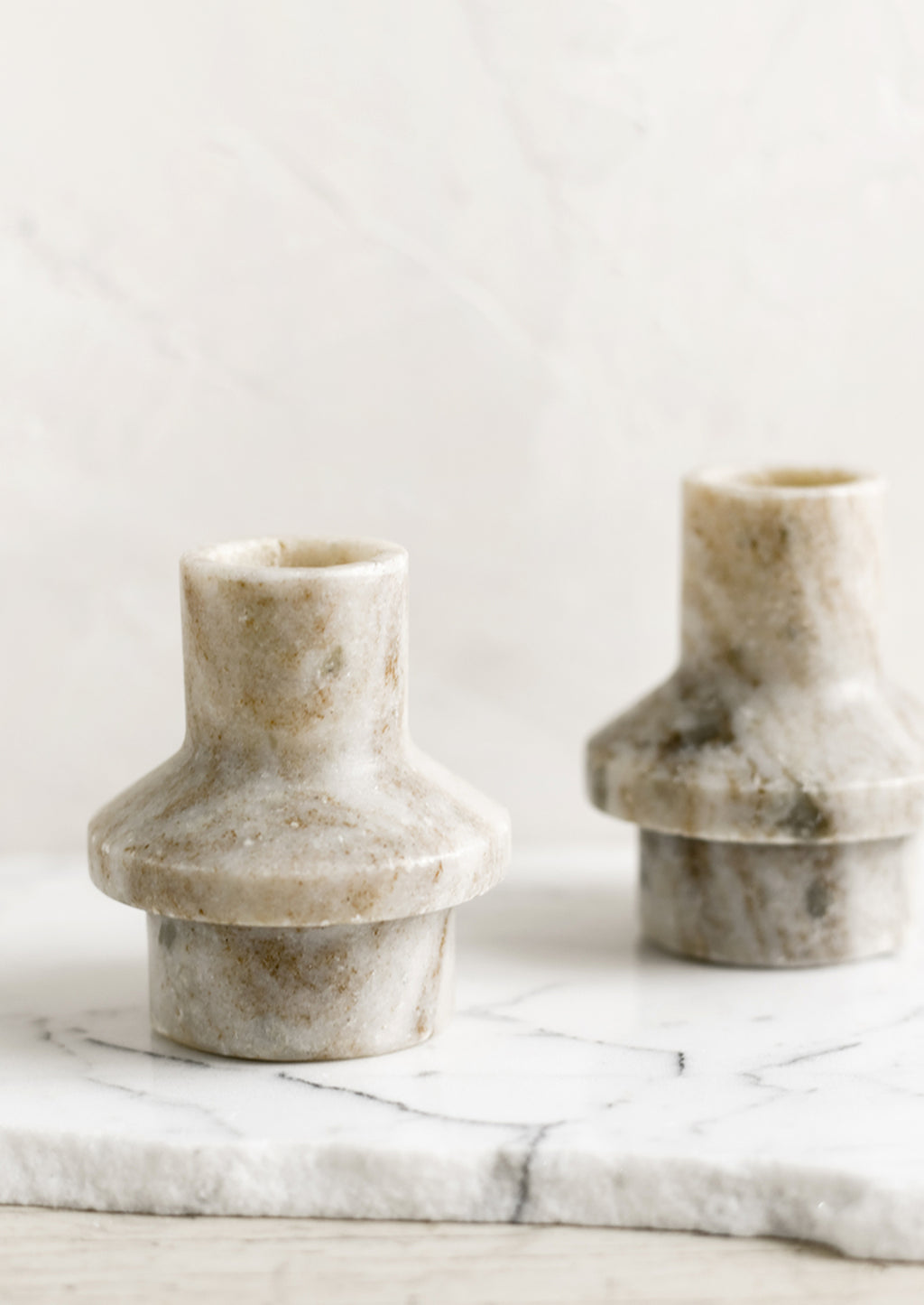 1: A taper candle holder in tan colored marble with sculptured shape.