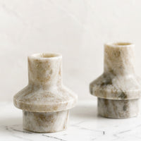 1: A taper candle holder in tan colored marble with sculptured shape.