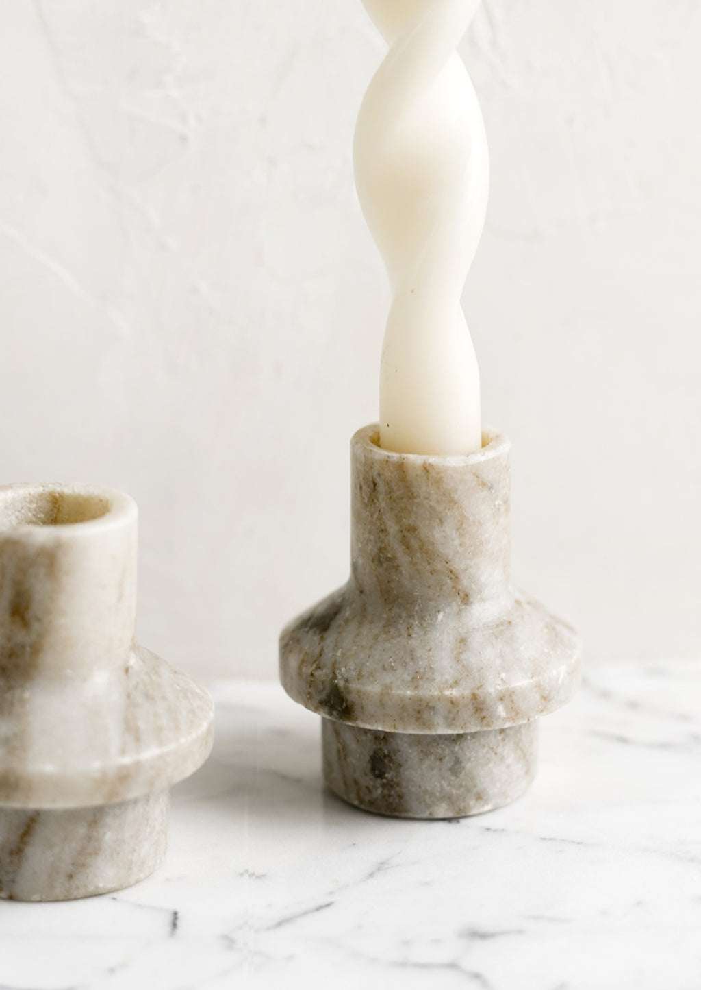 2: A taper candle holder in tan colored marble with sculptured shape.