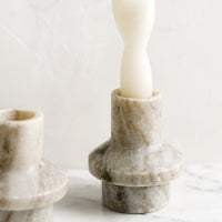 2: A taper candle holder in tan colored marble with sculptured shape.