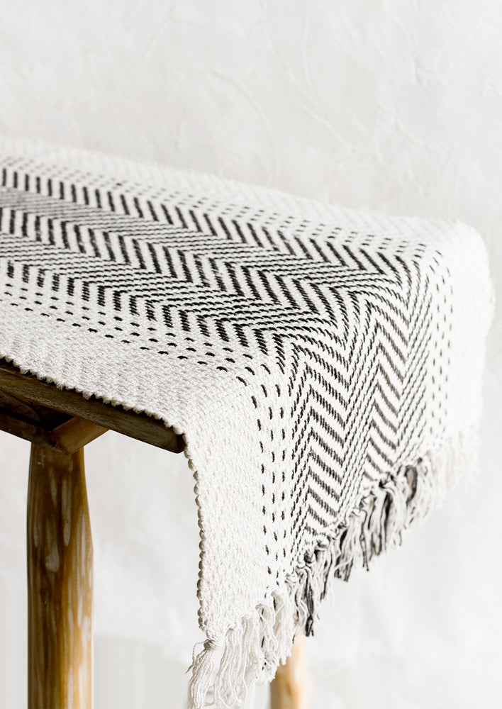 A cream textured cotton table runner with herringbone stitch down middle.