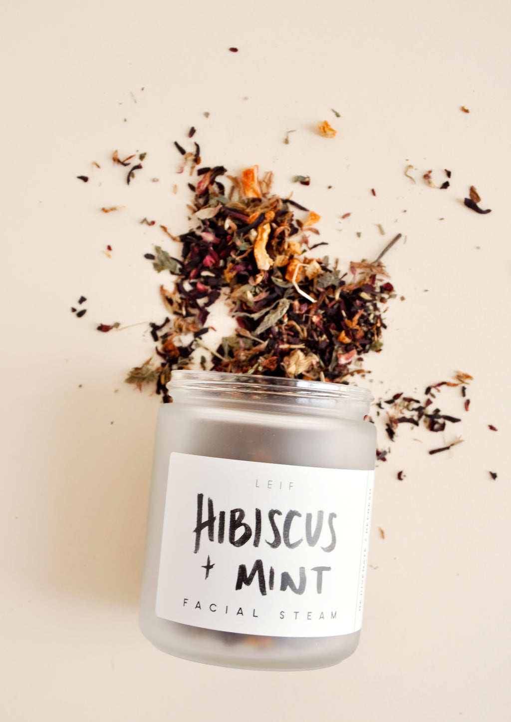1: A small frosted glass jar with a black and white label spilling out a mix of dried flowers. 