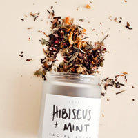 1: A small frosted glass jar with a black and white label spilling out a mix of dried flowers. 