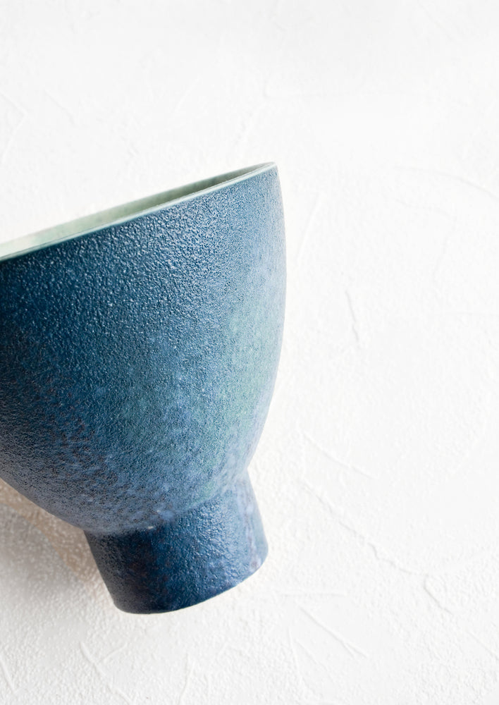 2: Round ceramic planter with tapered, footed silhouette. Textured deep blue glaze with turquoise interior.