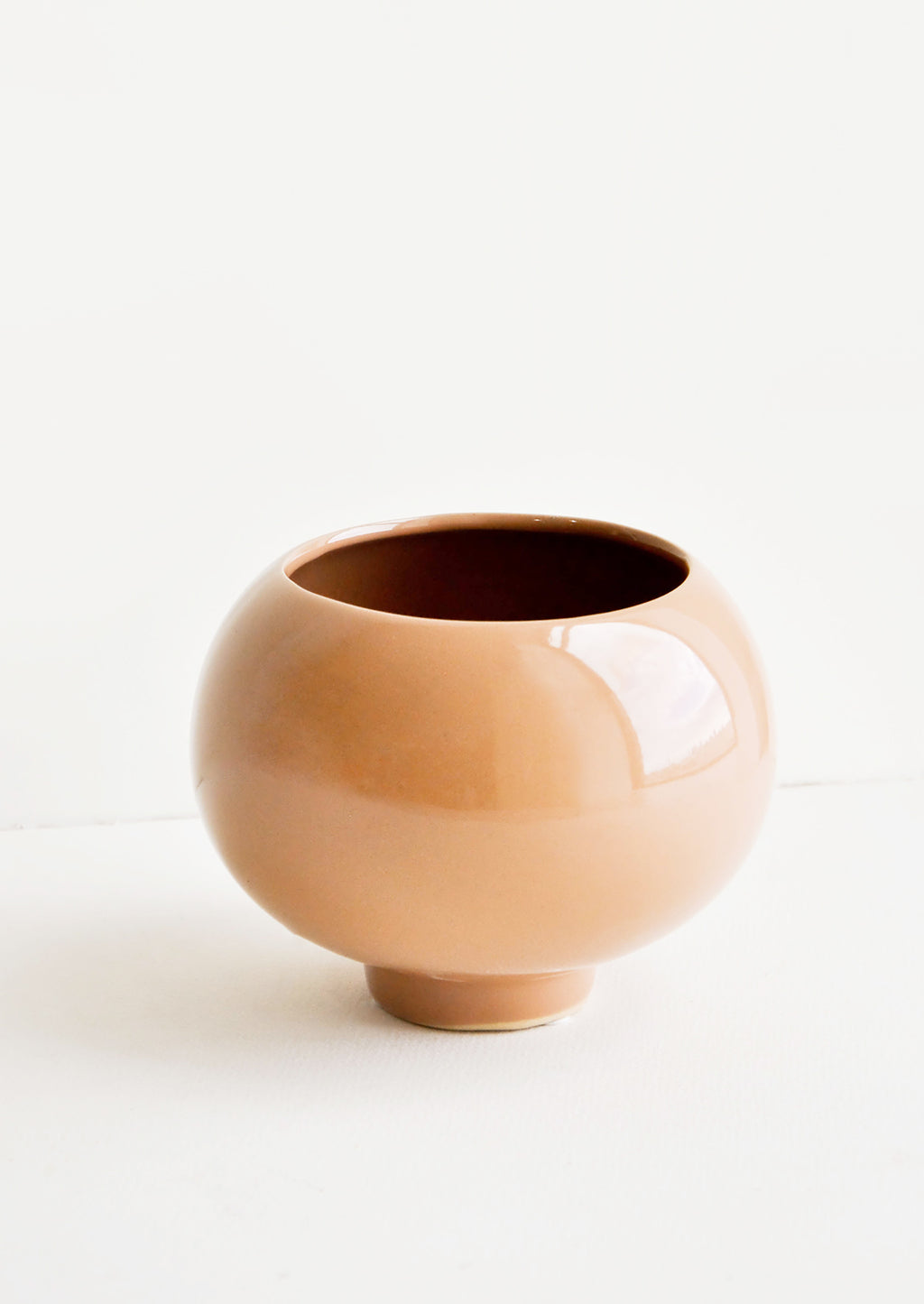 1: A ceramic planter in round shape with footed base and a glossy cocoa brown finish.