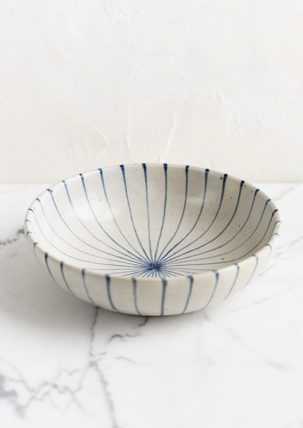 2: A round and shallow bowl in white with blue sunray pinstripe pattern.