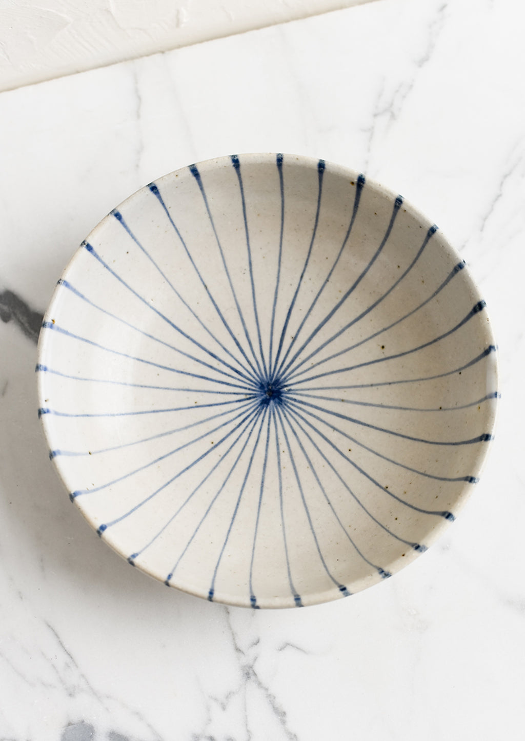 1: A round and shallow bowl in white with blue sunray pinstripe pattern.