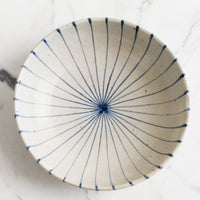 1: A round and shallow bowl in white with blue sunray pinstripe pattern.