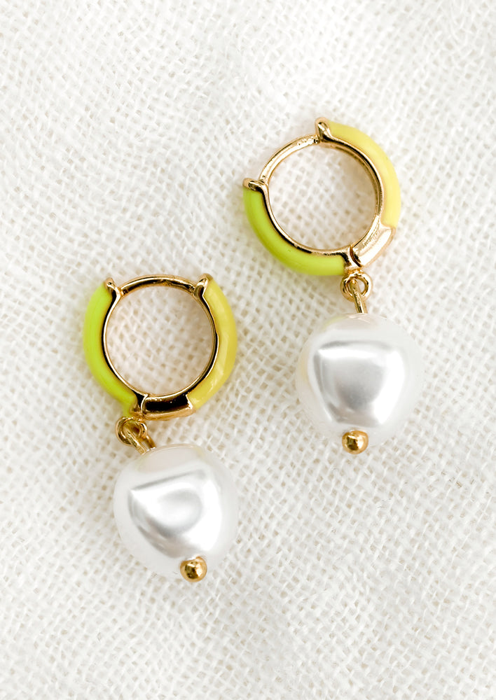 A pair of neon yellow and green huggie hoops with single pearl.