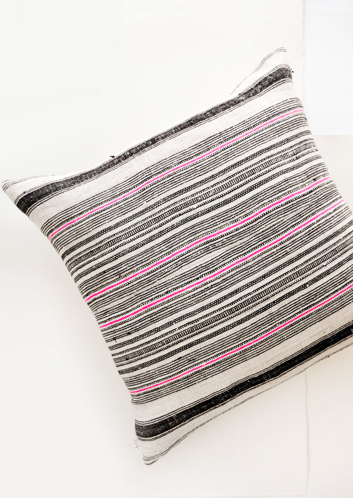 Square throw pillow in natural hemp fabric with varied stripes in black and hot pink