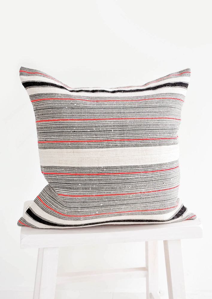 1: Square throw pillow in natural tan color with black and red variegated stripes