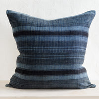 1: A square throw pillow in indigo fabric with variegated black stripes.
