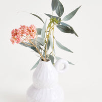 2: A small white ceramic vase with textured detailing, displaying a floral arrangement.