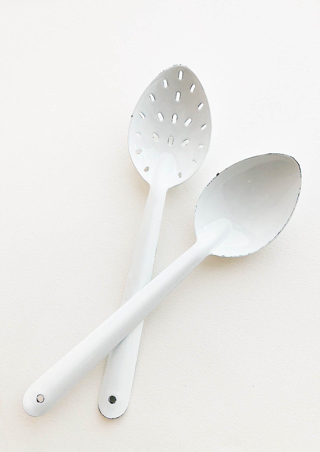 2: One regular and one slotted white enamel spoon.