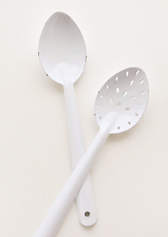 One regular and one slotted white enamel spoon.
