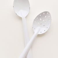 1: One regular and one slotted white enamel spoon.
