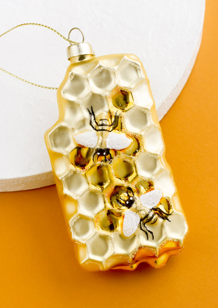 A decorative glass ornament of honeycomb with bees.