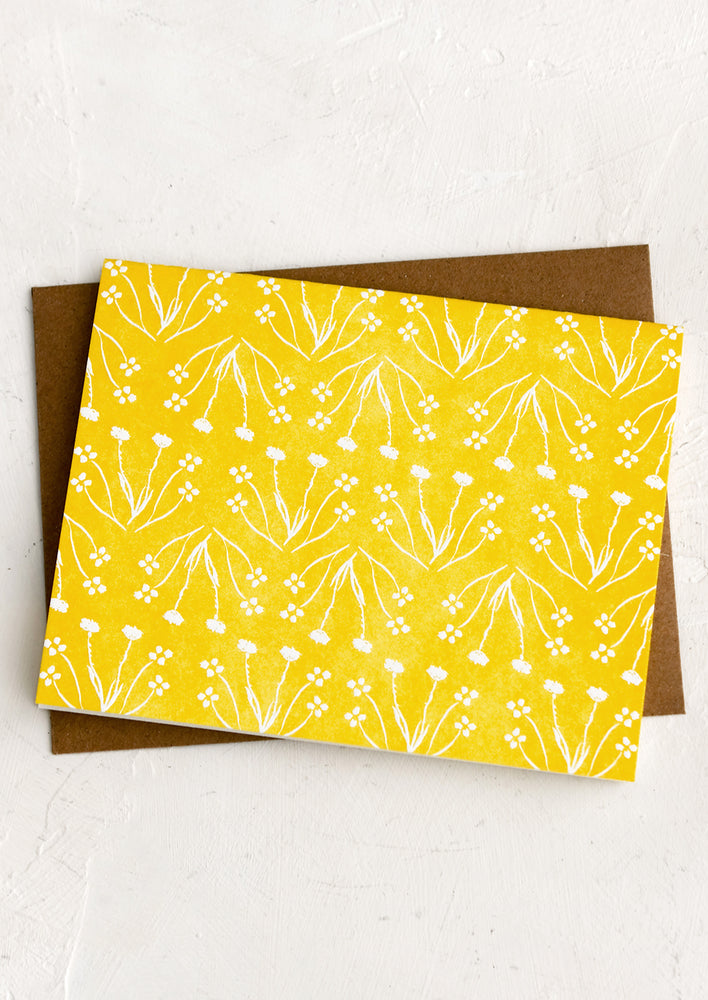 A yellow card with repeating white flower print.