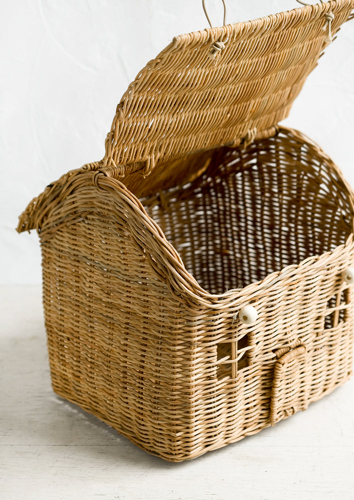 A rattan storage basket in the shape of a house.