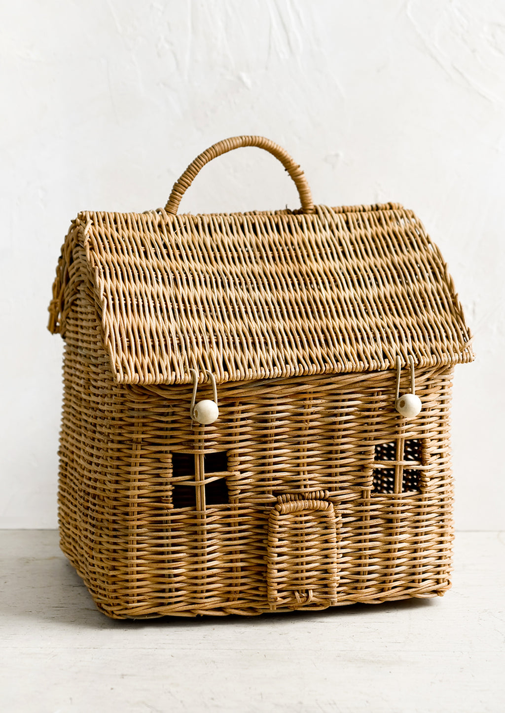 1: A rattan storage basket in the shape of a house.