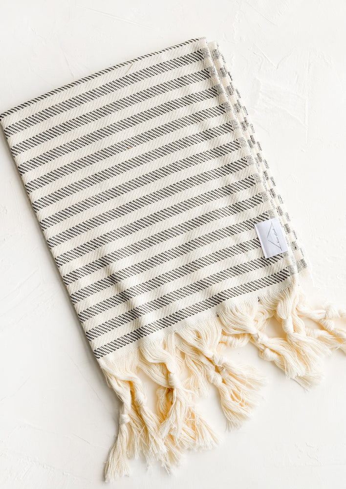 A turkish hand towel in natural with black stripes with natural fringed trim.