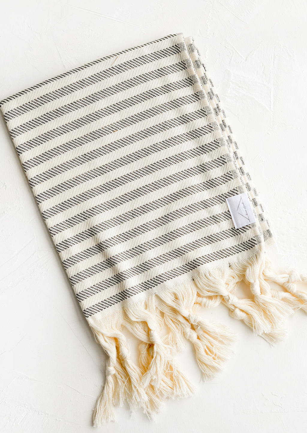 Abyss Stripe: A turkish hand towel in natural with black stripes with natural fringed trim.